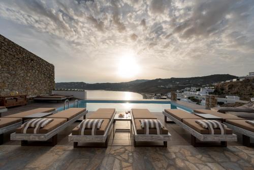 a swimming pool with beds on the roof of a building at Cova Mykonos Suites in Elia Beach