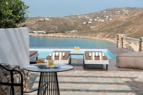 a patio with a table and chairs and a view of the ocean at Cova Mykonos Suites in Elia Beach