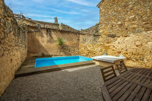 una piscina con tavolo e panca accanto a un edificio di Magnifique maison climatisée en pierre a Narbonne