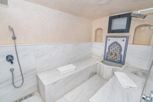 a white bathroom with a tub and a tv at Villa Ibn Batouta piscine 8x3 sans vis a vis in Tangier