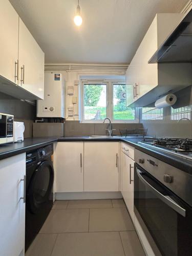 a kitchen with white cabinets and a sink and a dishwasher at 2 bed flat in Purley Less than 30 minutes to central London in Purley