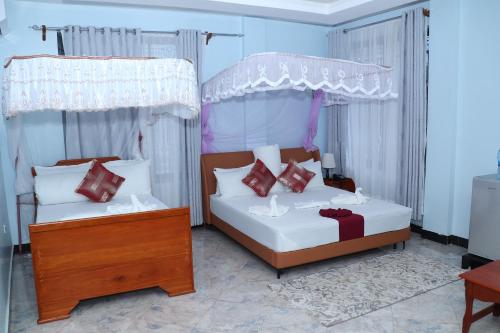 a bedroom with two beds with red and white pillows at MK Hotel in Muisenge