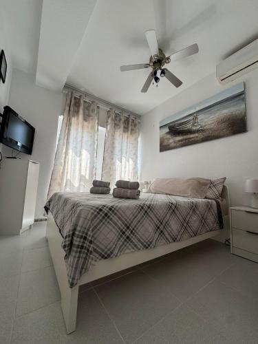 a bedroom with a bed with a ceiling fan at Beachfront apartment in La Mata in La Mata