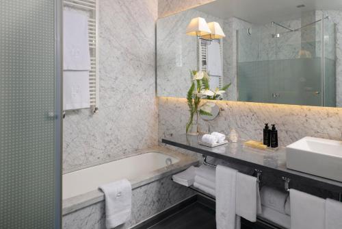 a bathroom with a bath tub and a sink and a mirror at URSO Hotel & Spa, a Small Luxury Hotel of the World in Madrid