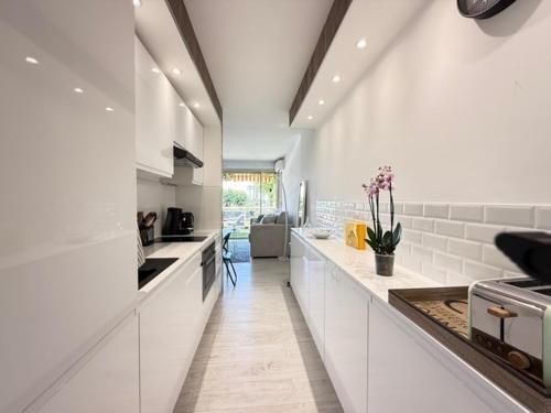 une grande cuisine blanche avec comptoirs et appareils blancs dans l'établissement Beach Studio in Golfe-Juan near Cannes and Antibes, au Golfe-Juan