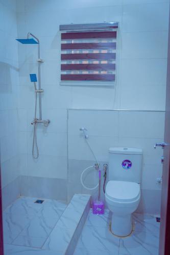a white bathroom with a toilet and a window at Hannan Residence in Abuja