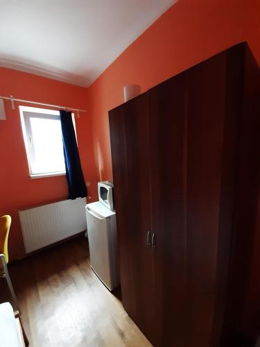 a small room with orange walls and a refrigerator at 2-Rent Group Hostel Rooms&Apartments TUB19A in Munich