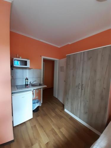 a kitchen with orange walls and a wooden floor at 2-Rent Group Hostel Rooms&Apartments TUB19A in Munich