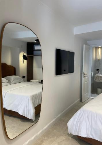 a mirror in a bedroom with two beds and a television at Caleda Rooms - Boutique Stay in Dubrovnik Center in Dubrovnik
