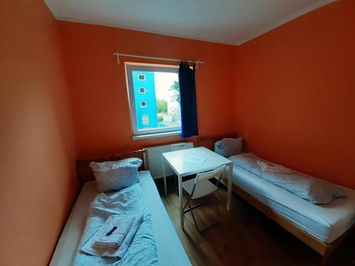 a room with two beds and a table and a window at 2-Rent Group Hostel Rooms&Apartments TUB19A in Munich