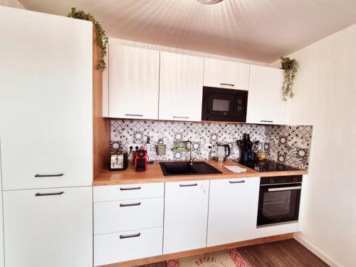 une cuisine blanche avec des armoires blanches et un micro-ondes dans l'établissement L'Opale, appartement neuf by Primo, à Cucq
