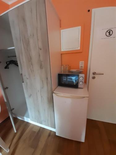 a small kitchen with a door and a microwave at 2-Rent Group Hostel Rooms&Apartments TUB19A in Munich