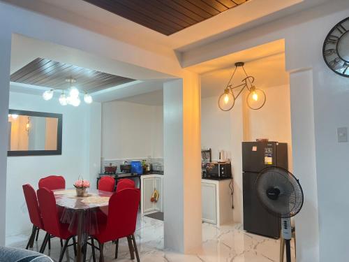 a kitchen and dining room with a table and red chairs at Loven Transient House in Dauis