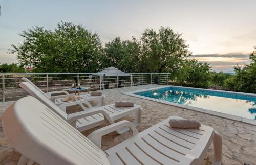 a pool with white lounge chairs and a swimming pool at Villa Stella ZadarVillas in Gornje Biljane