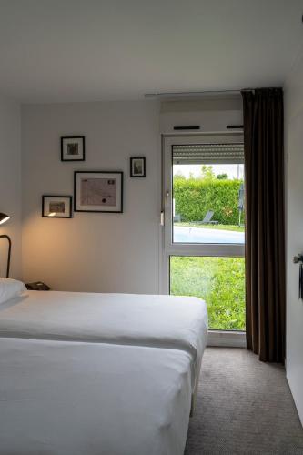 une chambre avec un lit et une grande fenêtre dans l'établissement Kyriad Nuits Saint Georges Dijon Sud, à Nuits-Saint-Georges