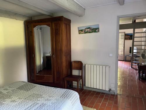 a bedroom with a bed and a mirror and a chair at Mas Grimaud - Gîte- Studio et chambres d'hôtes familiales in Eygalières