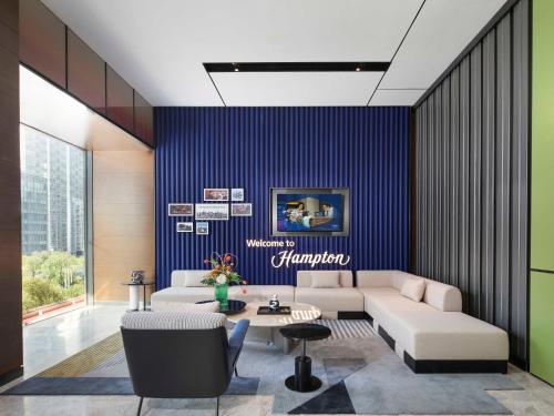 a living room with a couch and a blue wall at Hampton by Hilton Chengdu Wuhou Waishuannan in Chengdu