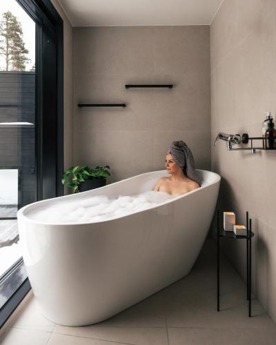 a woman sitting in a bath tub in a bathroom at Polaris Villas in Muonio