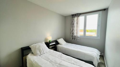 deux lits dans une chambre avec une fenêtre dans l'établissement Lumière et océan, T3 face mer, à Saint-Jean-de-Monts