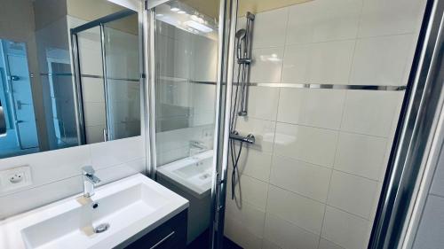 une salle de bain blanche avec un lavabo et une douche dans l'établissement Lumière et océan, T3 face mer, à Saint-Jean-de-Monts
