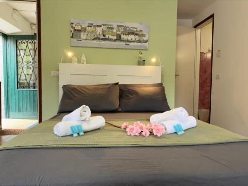 a bed with two towels and flowers on it at Sussurro del Lago - A due passi dal Traghetto in Tremezzo