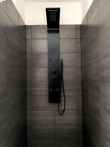 une douche avec un pommeau de douche noir sur un mur dans l'établissement Charmante maison à Garrigues St-Eulalie, à Collorgues