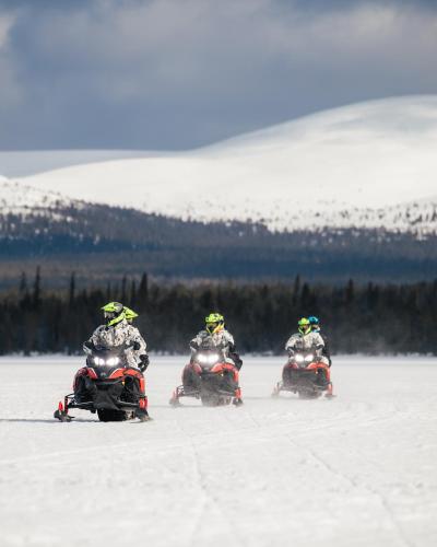 three people are riding on atvs in the snow at Polaris Villas in Muonio