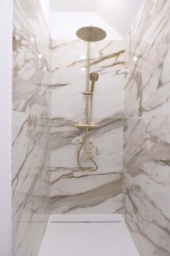 La salle de bains est pourvue d'une douche et de murs en marbre. dans l'établissement La Petite Maison, à Bligny-lès-Beaune