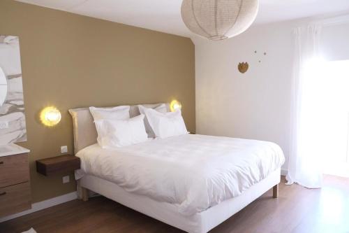 une chambre avec un lit avec des draps blancs et des oreillers dans l'établissement La Petite Maison, à Bligny-lès-Beaune