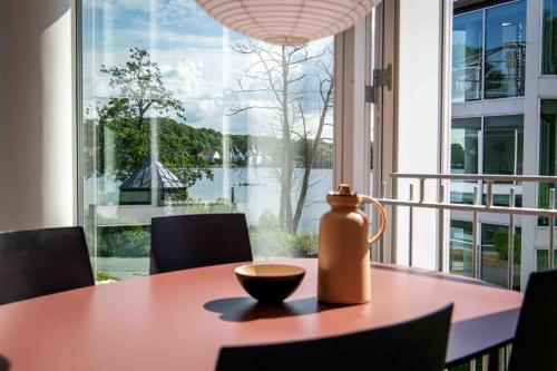 a table with a vase sitting on top of it in front of a window at Kolding Hotel Apartments in Kolding