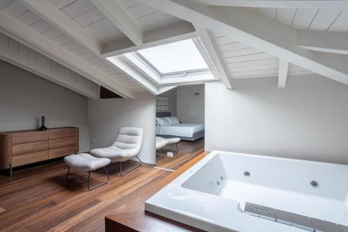 a room with a tub and two chairs and a bedroom at BePlace Apartments Arona in Arona