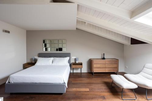 a white bedroom with a bed and a chair at BePlace Apartments Arona in Arona