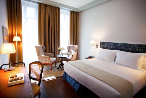 a hotel room with a bed and a table and chairs at URSO Hotel & Spa, a Small Luxury Hotel of the World in Madrid