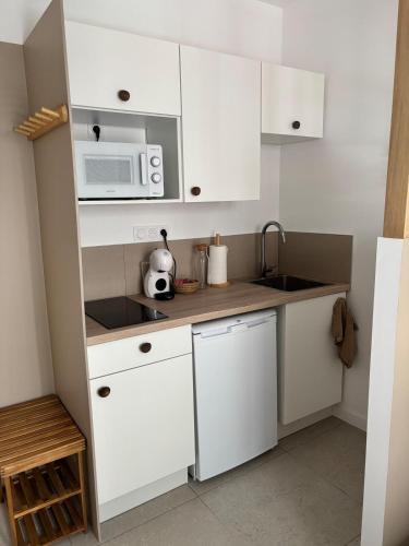 une petite cuisine avec des armoires blanches et un micro-ondes dans l'établissement La parenthèse balinaise, à Cholet