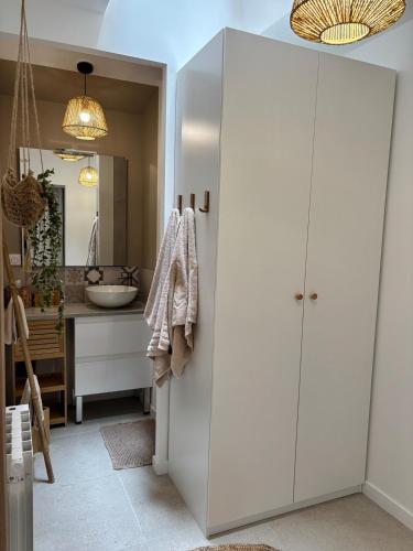La salle de bains est pourvue d'une armoire blanche et d'un lavabo. dans l'établissement La parenthèse balinaise, à Cholet