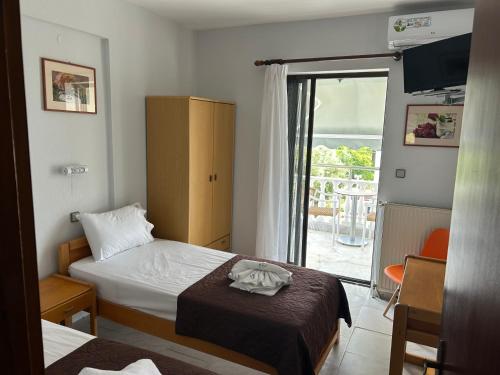 a hotel room with two beds and a window at Dionisos Roses in Paralia Dionysiou