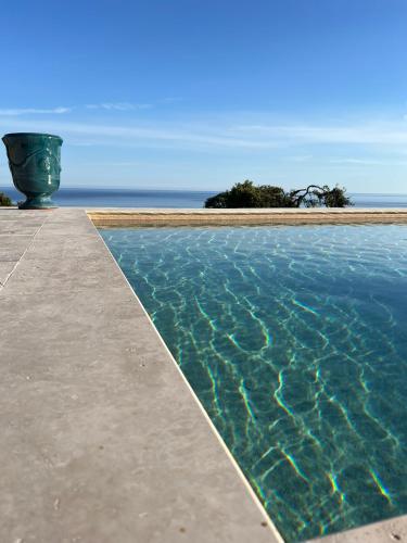 une piscine avec l'océan en arrière-plan dans l'établissement LUMIO Élégance & Calme absolu avec piscine et vue mer, à Lumio