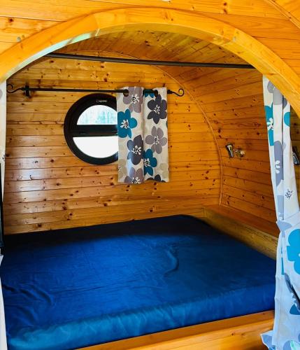 Ce lit se trouve dans une chambre en bois dotée d'une fenêtre. dans l'établissement barrique viticole, à Le Tartre