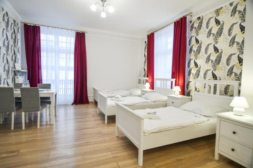 a room with four beds and a dining room with red curtains at Dom Zdrojowy w Szczawnie - Zdroju in Szczawno-Zdrój