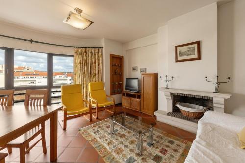 a living room with a table and chairs and a fireplace at Sunset Bay São Martinho do Porto in São Martinho do Porto