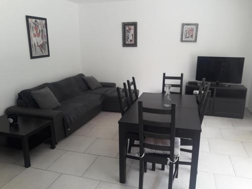 un salon avec un canapé noir et une table dans l'établissement Briloc Appartements Pietrosella à 50m de la plage, à Pietrosella