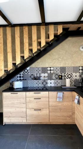 - une cuisine avec des placards en bois et du carrelage noir et blanc dans l'établissement Gîte charme et nature Drôme, à Chantemerle-les-Blés