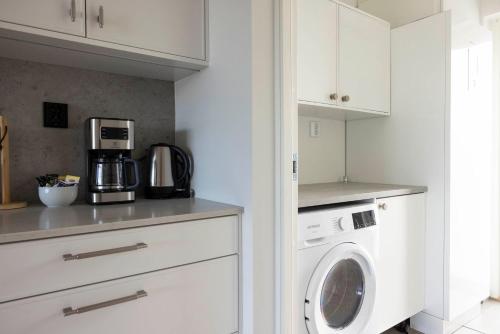 a white kitchen with a washer and dryer at Varvet Sea View Suites by Ålandhotels in Mariehamn