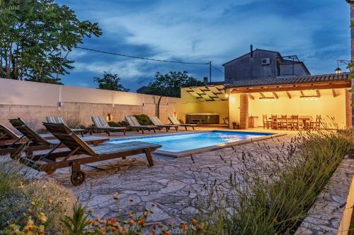 a swimming pool with lounge chairs and a house at Villa Katja near Pula with whirlpool only 3 km from the beach in Krnica