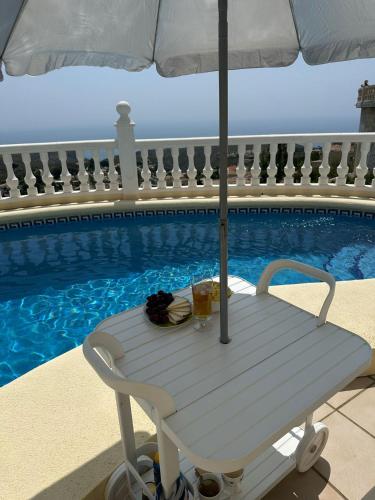 a white bench with an umbrella next to a swimming pool at Villa Maravista - Luxury Villa with Private Pool and Sea View in Benitachell