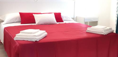 a bed with red sheets and white towels on it at Sa Trunfa Rooms in Tortolì