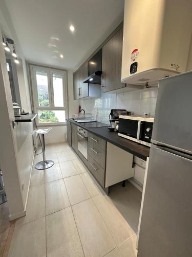 une cuisine avec des appareils en acier inoxydable et un comptoir noir dans l'établissement Cozy, bright apartment - Disney - private parking, à Rosny-sous-Bois