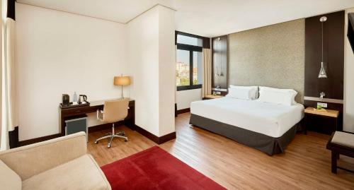 a hotel room with a bed and a desk and a chair at NH Avenida Jerez in Jerez de la Frontera