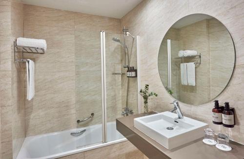 a bathroom with a sink and a shower and a mirror at NH Avenida Jerez in Jerez de la Frontera
