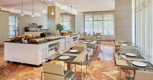 a restaurant with tables and chairs and a counter with food at NH Avenida Jerez in Jerez de la Frontera